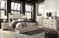 Cama Cambeck tamaño King con cabecero y cuatro cajones, tocador con espejo, cómoda y mesita de noche.