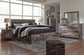 Cama Derekson tamaño King con cabecero y cuatro cajones, tocador con espejo, cómoda y mesita de noche.